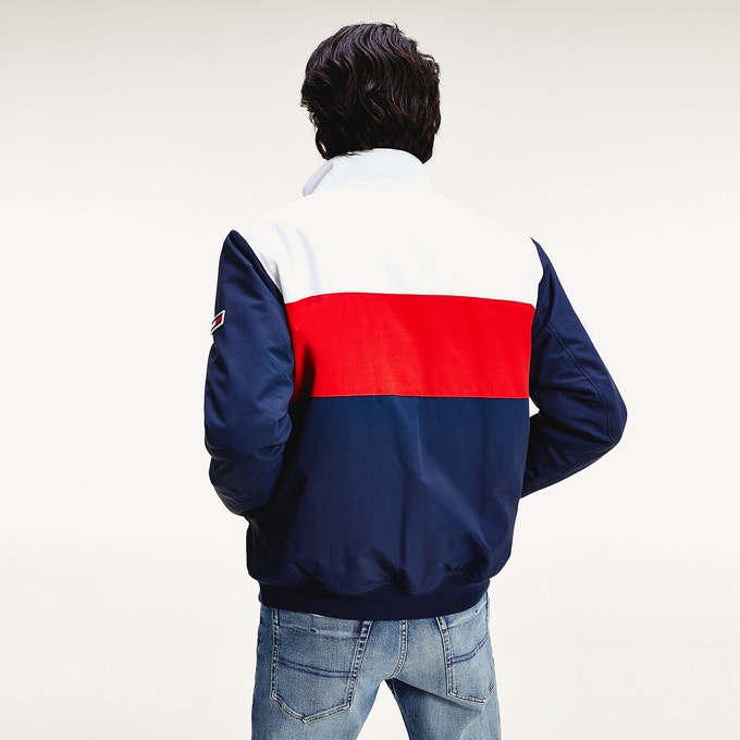 Man facing the other way wearing a red, blue and white Tommy Jeans jacket with high-neck and zip fastening