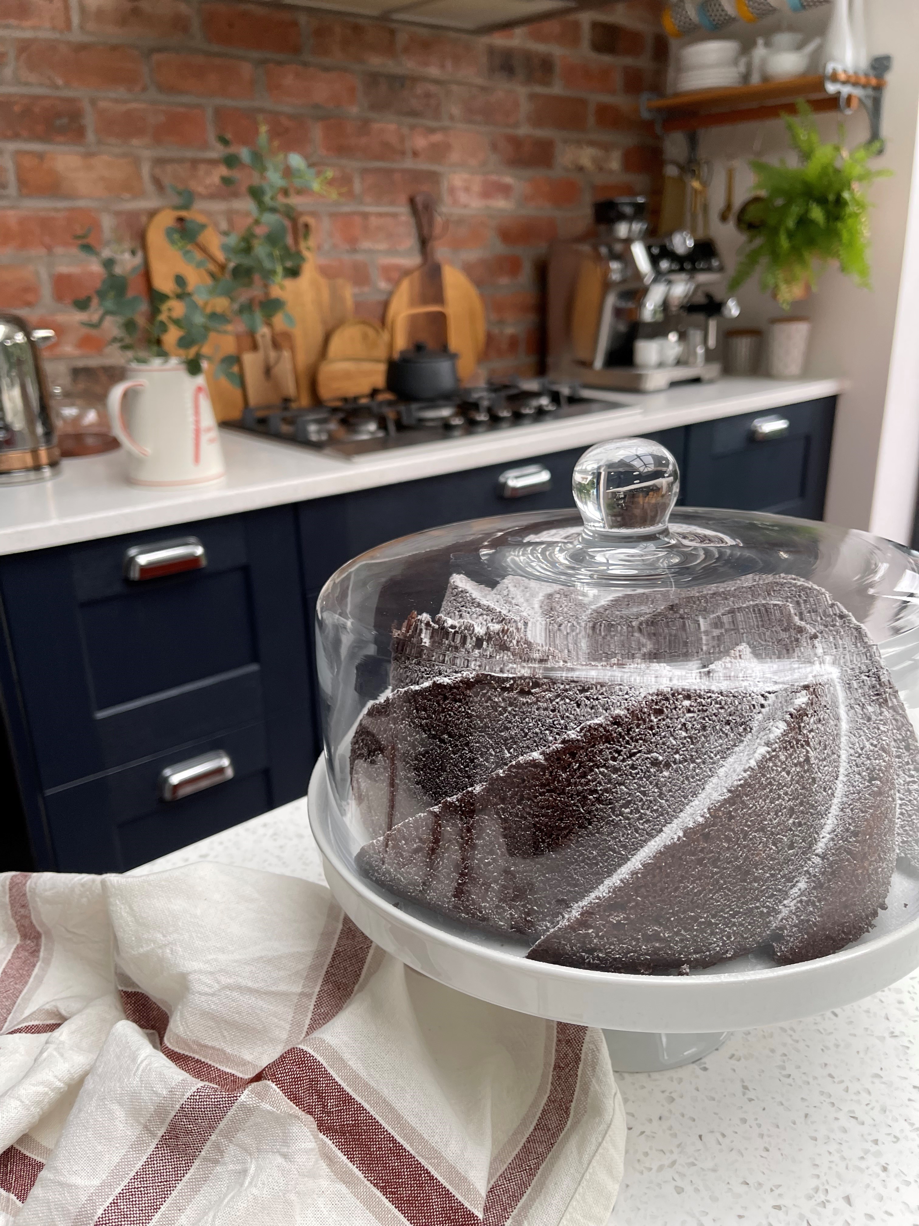 Chocolate cake in a ceramic dish with kitchen in the background