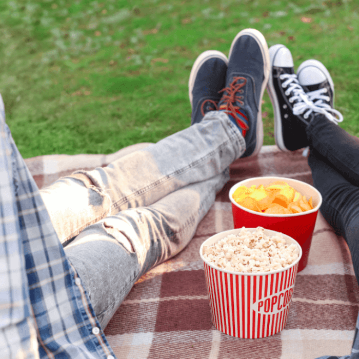 couple-sharing-popcorn-crisps-outdoors-on-blanket.png