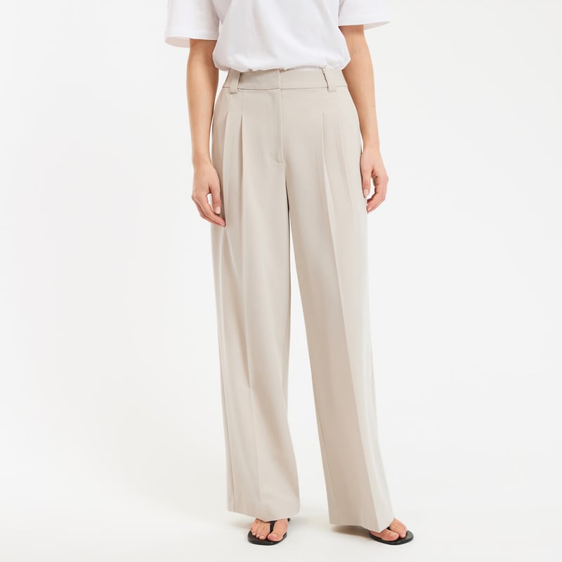 Pantalon beige large avec haut blanc, look sobre et &eacute;l&eacute;gant.
