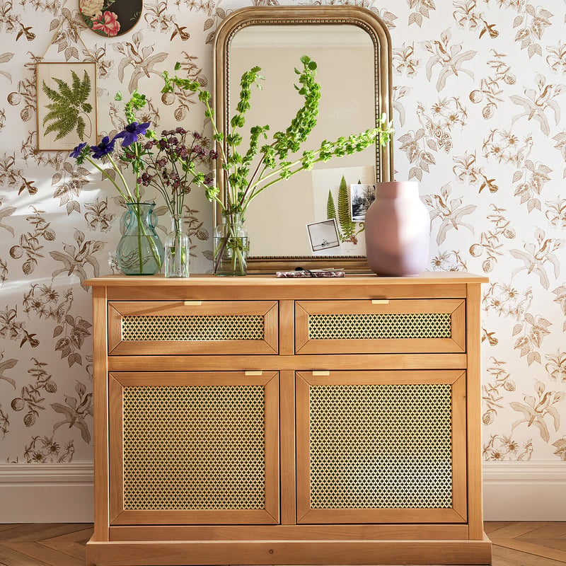 Miroir au-dessus d&rsquo;un buffet en bois, fleurs et vase d&eacute;coratif.