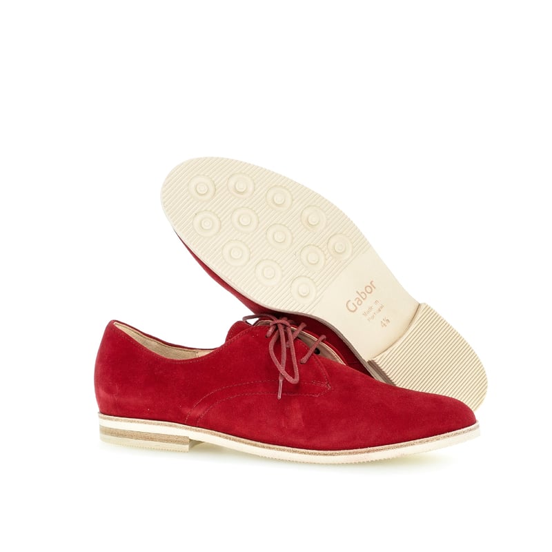 Chaussures en daim rouge, dont une semelle visible sur fond blanc