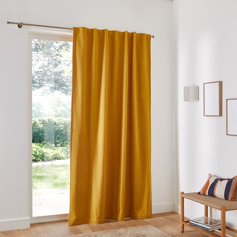 Mustard thermal curtain covering tall windows in bright home interior