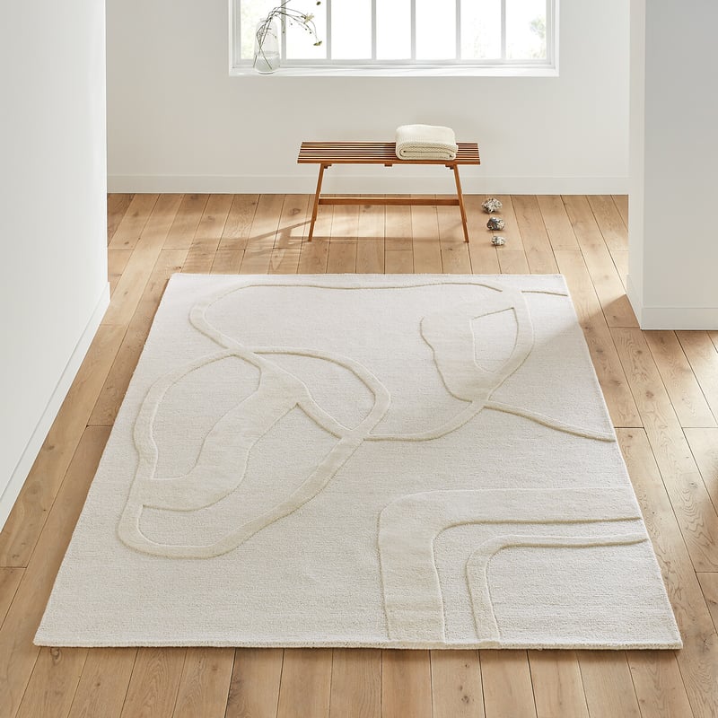 Tapis clair pos&eacute; sur parquet dans une pi&egrave;ce lumineuse et &eacute;pur&eacute;e