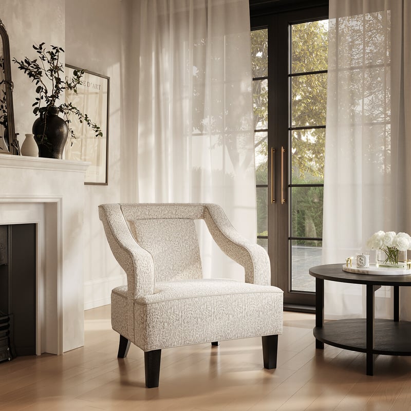 Comfortable reading armchair beside tall windows in a calm, elegant living room